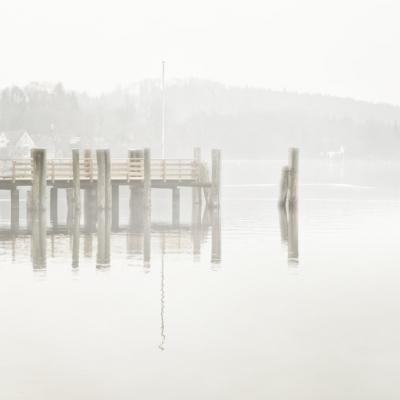Ein Steg am Ammersee ist umhüllt von leichten Nebel.