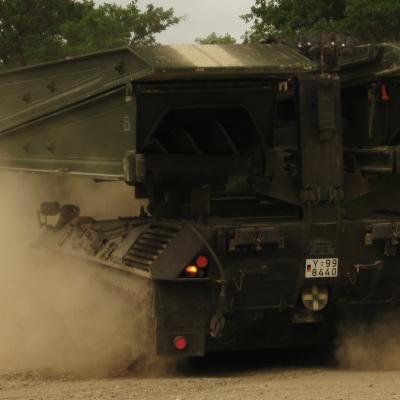 Ein Panzer von Typ Biber verrichtet seine Arbeit. Die Ketten sind umhüllt von Staub.