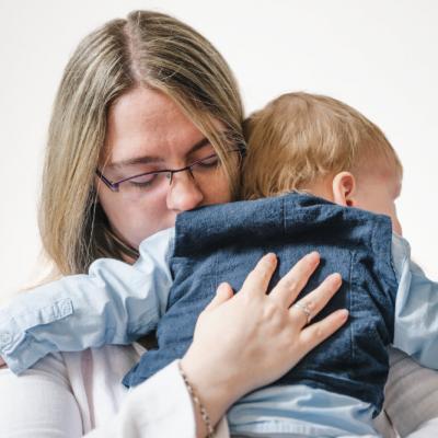 Eine Mutter hält ihr weinendes Kind, ihre Augen geschlossen, während sie es tröstet.